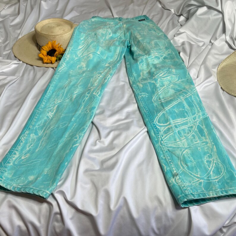 Op de afbeelding: Een lichtblauwe jeans met een wit tie-dye patroon. De jeans heeft een ontspannen pasvorm en een rechte pijp.