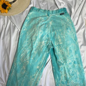 Op de afbeelding: Een lichtblauwe spijkerbroek met een wit tie-dye patroon. De broek heeft een hoge taille en een rechte pijp.