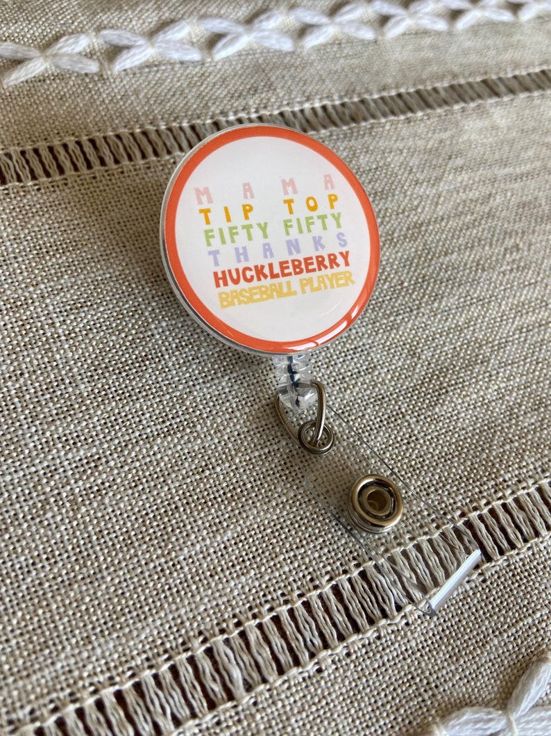 May include: A colorful badge holder with the text "Mama Tip Top Fifty Fifty Thanks Huckleberry Baseball Player".