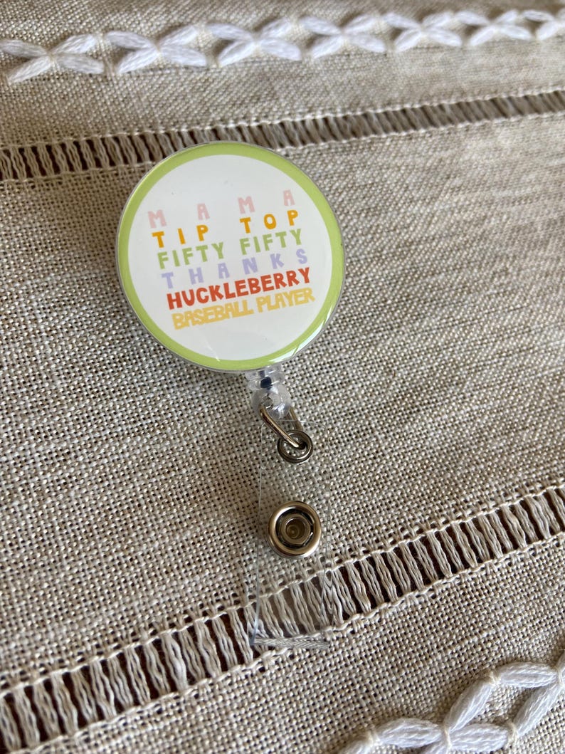 May include: A green, yellow, pink, and blue badge holder with the text "Mama Tip Top Fifty Fifty Thanks Huckleberry Baseball Player".