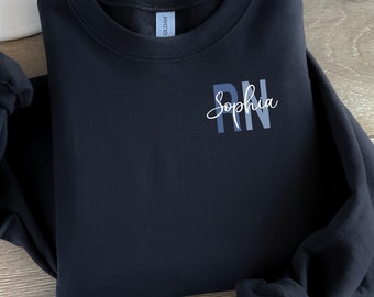 May include: Black sweatshirt with the text "Sophia RN" in a blue gradient on the front.