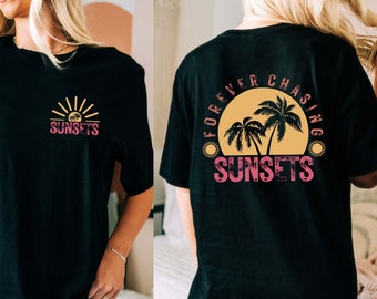 May include: Black oversized t-shirt with a graphic print of a sunset and palm trees. The front of the shirt says "SUNSETS" and the back says "FOREVER CHASING SUNSETS".