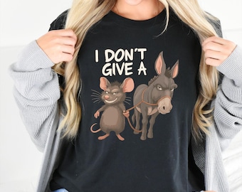 May include: Black t-shirt with the phrase "I DON'T GIVE A" in white block letters. The graphic features a smiling brown mouse holding a leash attached to a gray donkey with a stern expression. The shirt is a casual wear item.