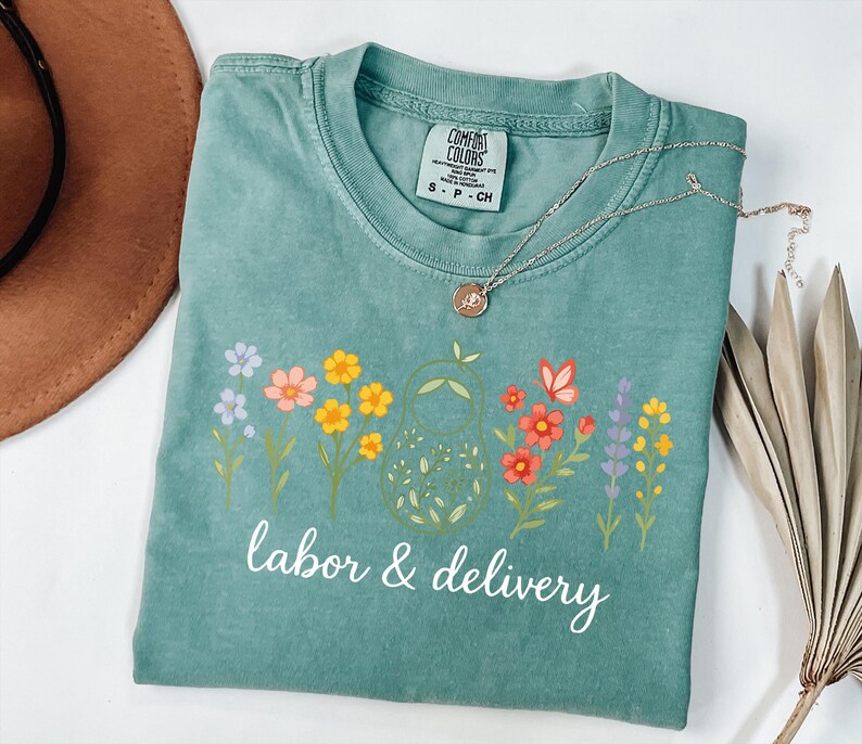 May include: A teal blue t-shirt with a floral design and the text "labor & delivery" in white.