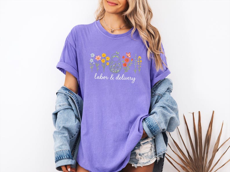 May include: Purple t-shirt with a floral design and the text "labor & delivery" in white.