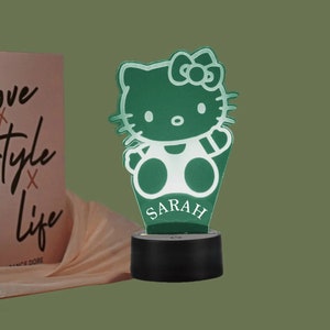 May include: Green Hello Kitty night light with a white base and the name "SARAH" printed on the front.
