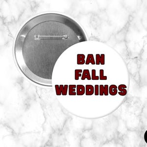 Może przedstawiać: Biała przypinka z napisem "BAN FALL WEDDINGS" pogrubioną, ciemnoczerwoną czcionką. Przypinka ma metalowe zapięcie i jest umieszczona na marmurowym tle. Przypinka jest okrągła i ma błyszczącą, metalową krawędź.