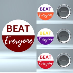 May include: Three round button pins with the text "BEAT Everyone" in white letters on a red, orange, and purple background. The buttons have a silver metal backing.