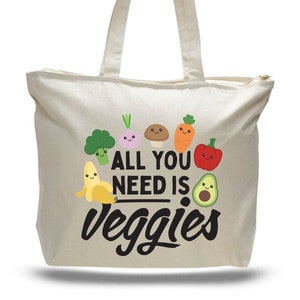 beige canvas bag with top zipper. Printed with adorable cartoon vegetables with message that says "All you need is veggies"
