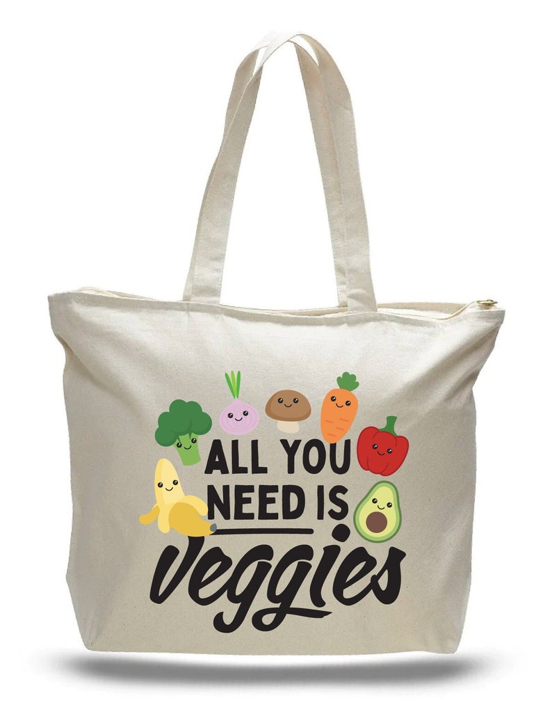 beige canvas bag with top zipper. Printed with adorable cartoon vegetables with message that says "All you need is veggies"