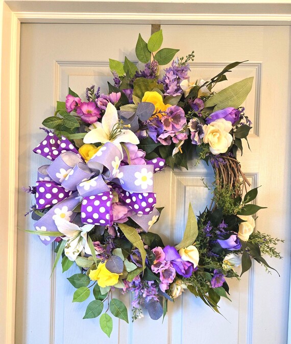 Easter or Spring Wreath with florals done in various shades of Purple, cream and white with a burst of yellow.
