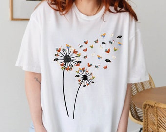 May include: White t-shirt with a graphic of two dandelions. The dandelions are made up of small colorful chickens.