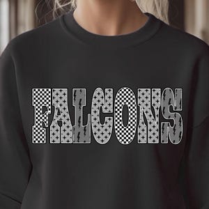 May include: Black sweatshirt with the word "FALCONS" in large, bold letters across the front. The letters have a checkered pattern and gray lightning bolt accents. The sweatshirt is a solid black color.