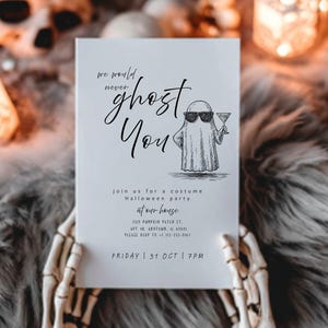 May include: A white Halloween party invitation with the text "we would never ghost you". The invitation features a cartoon ghost wearing sunglasses and holding a cocktail. The invitation is held by a skeleton hand.