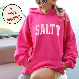May include: A bright pink hoodie with the word "SALTY" printed in white across the chest. The hoodie has a hood, a front pocket, and long sleeves. The image also includes a circular graphic that says "4 PNG'S INCLUDED".