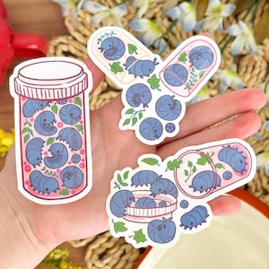 May include: A collection of stickers featuring cartoon pill bugs in various designs. One sticker shows a pill bottle filled with the blue bugs. Other stickers depict the bugs in capsules and petri dishes, with green leaf accents.