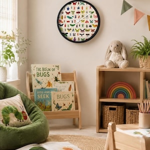 May include: A round wall clock with a black frame featuring a cream-colored face covered in a repeating pattern of colorful, detailed illustrations of various insects, beetles, and butterflies, complete with thin white hour and minute hands.