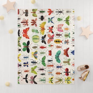 Può includere: Una coperta bianca con un motivo colorato di vari insetti, tra cui farfalle, coleotteri e libellule. Gli insetti sono raffigurati in uno stile stravagante e da cartone animato con una varietà di colori, come rosso, verde, blu e giallo.