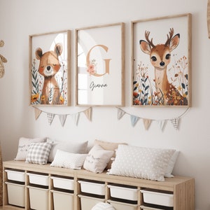 Può includere: Una cameretta con una panca portaoggetti in legno con contenitori bianchi. La panca è decorata con una ghirlanda di bandierine. Tre stampe incorniciate con illustrazioni di animali sono appese al muro sopra la panca. Le stampe raffigurano un cervo, un orso e una lettera G con fiori. Il testo "Grandma" è scritto sotto la lettera G.