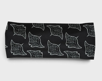 May include: A black rectangular headband featuring a repeating white line art pattern of manta rays. The design consists of multiple manta ray silhouettes arranged in a scattered layout across the entire surface of the fabric accessory.
