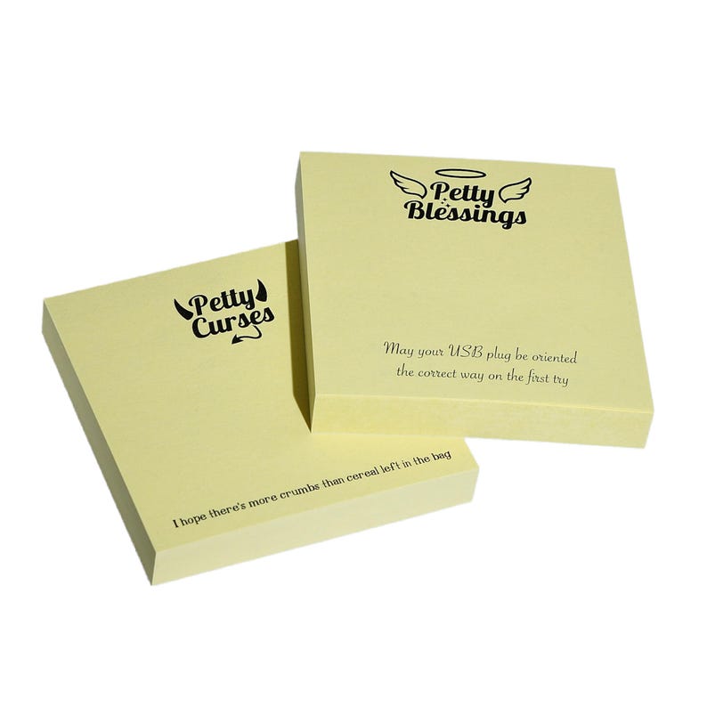 May include: Two yellow sticky note pads with black text. The top pad says "Petty Blessings" with a halo and wings. The bottom pad says "Petty Curses" with devil horns and a tail. The bottom pad also has the text "May your USB plug be oriented the correct way on the first try" and "I hope there's more crumbs than cereal left in the bag."