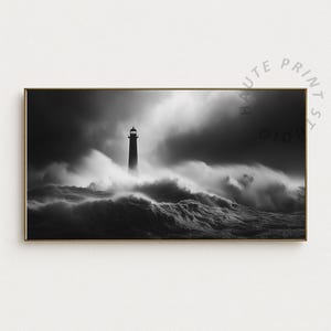 May include: Black and white framed print of a lighthouse amidst a stormy sea. The lighthouse stands tall, illuminated against a dark, cloudy sky. Waves crash around the base of the lighthouse, creating a dramatic and powerful scene. The print has a gold frame.