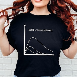 May include: Black t-shirt with a white graph and the text "Well... we're skewed." The graph depicts three curved lines. The shirt is made of a soft material.