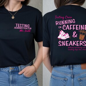 May include: Black t-shirt with pink text. Front reads "TESTING ADMINISTRATOR Mrs. Smith". Back reads "Testing Crew RUNNING ON CAFFEINE & SNEAKERS" with images of sneakers and a coffee cup. "Actively monitoring and counting steps like a boss" is also printed.