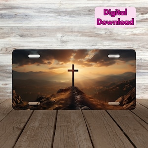 May include: A digital download of a license plate featuring a wooden cross silhouetted against a sunset over a mountain range.