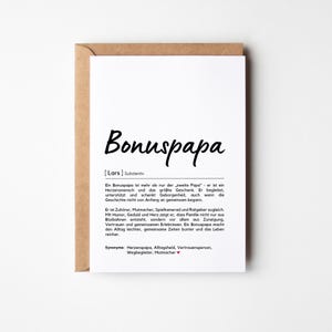 May include: A greeting card with a kraft paper envelope. The white card features the word "Bonuspapa" in a handwritten style, with German text below. The card is a thoughtful gift for a stepfather.