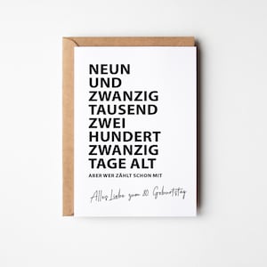 K&ouml;nnte beinhalten: Eine wei&szlig;e Gru&szlig;karte mit schwarzem Text, in einem braunen Umschlag. Die Karte lautet "NEUN UND ZWANZIG TAUSEND ZWEI HUNDERT ZWANZIG TAGE ALT" und "Alles Liebe zum 80. Geburtstag."
