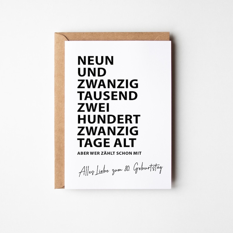K&ouml;nnte beinhalten: Eine wei&szlig;e Gru&szlig;karte mit schwarzem Text, in einem braunen Umschlag. Die Karte lautet "NEUN UND ZWANZIG TAUSEND ZWEI HUNDERT ZWANZIG TAGE ALT" und "Alles Liebe zum 80. Geburtstag."