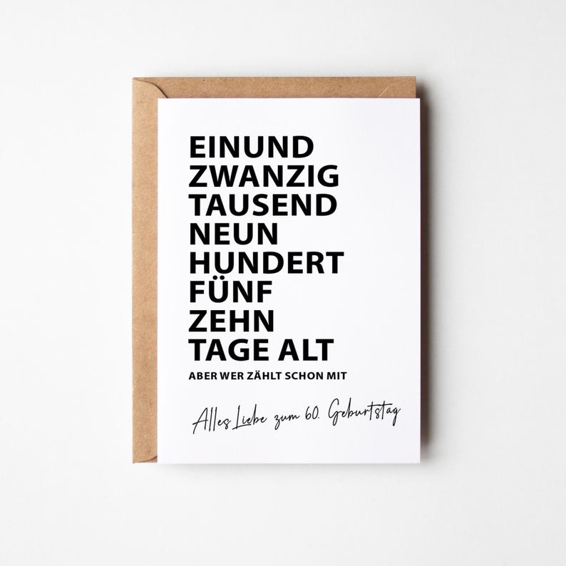 K&ouml;nnte beinhalten: Eine wei&szlig;e Gru&szlig;karte mit schwarzem Text, in einem braunen Umschlag. Der Text lautet "EINUND ZWANZIG TAUSEND NEUN HUNDERT F&Uuml;NF ZEHNTAGE ALT" und "Alles Liebe zum 60. Geburtstag". Die Karte ist f&uuml;r einen 60. Geburtstag.