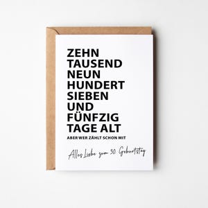 K&ouml;nnte beinhalten: Eine wei&szlig;e Gru&szlig;karte mit schwarzem Text in einem braunen Umschlag. Auf der Karte steht "ZEHN TAUSEND NEUN HUNDERT SIEBEN UND F&Uuml;NFZIG TAGE ALT" und "Alles Liebe zum 30. Geburtstag."