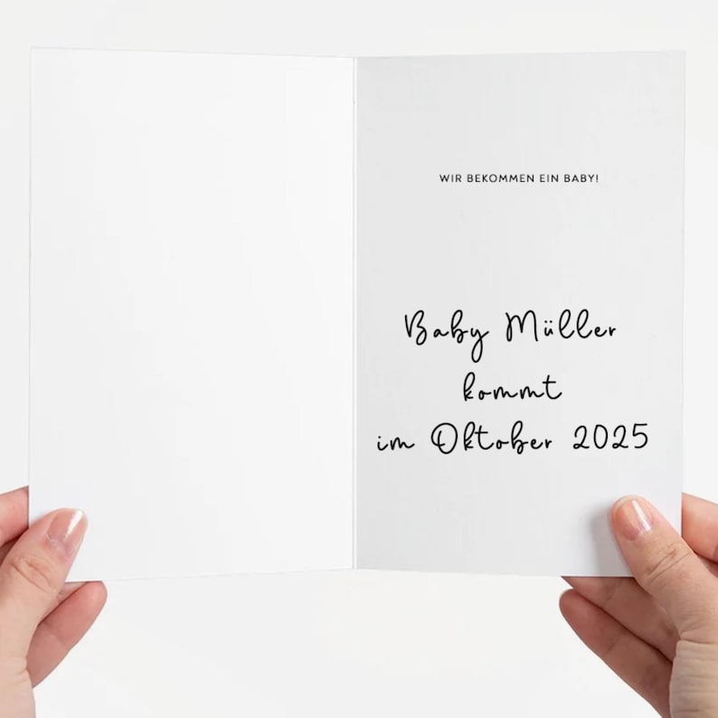 May include: A white card with the text "Wir bekommen ein Baby!" and "Baby M&uuml;ller kommt im Oktober 2025".