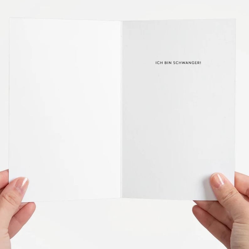 May include: A blank white card with the text "Ich bin schwanger!" printed in black on the right side.