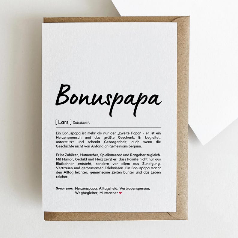 May include: A greeting card with the word "Bonuspapa" in large, black script. The card is white with text in German, and is inside a brown envelope. The card's text describes the meaning of "Bonuspapa".