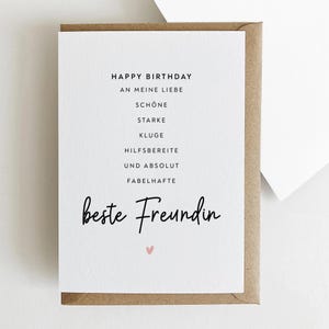 May include: A white greeting card with the words "Happy Birthday" and other German phrases in black text. The card is in a brown envelope, with a small pink heart at the bottom.