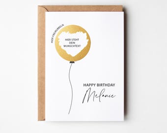 Könnte beinhalten: Eine weiße Geburtstagskarte mit einem goldenen Ballon-Design und dem Text "Happy Birthday Melanie". Die Karte enthält den Text "Hier steht dein Wunschtext" im Ballon. Die Karte befindet sich in einem braunen Umschlag.