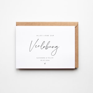 Könnte beinhalten: Eine weiße Karte mit den Worten "ALLES LIEBE ZUR Verlobung" in schwarzer Schrift, mit den Namen "ALEXANDRA & PHILIPP" und dem Datum "05.07.2026" darunter. Die Karte befindet sich in einem braunen Umschlag.