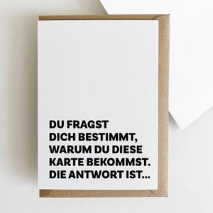 May include: A white card with black text that reads "DU FRAGST DICH BESTIMMT, WARUM DU DIESE KARTE BEKOMMST. DIE ANTWORT IST..."