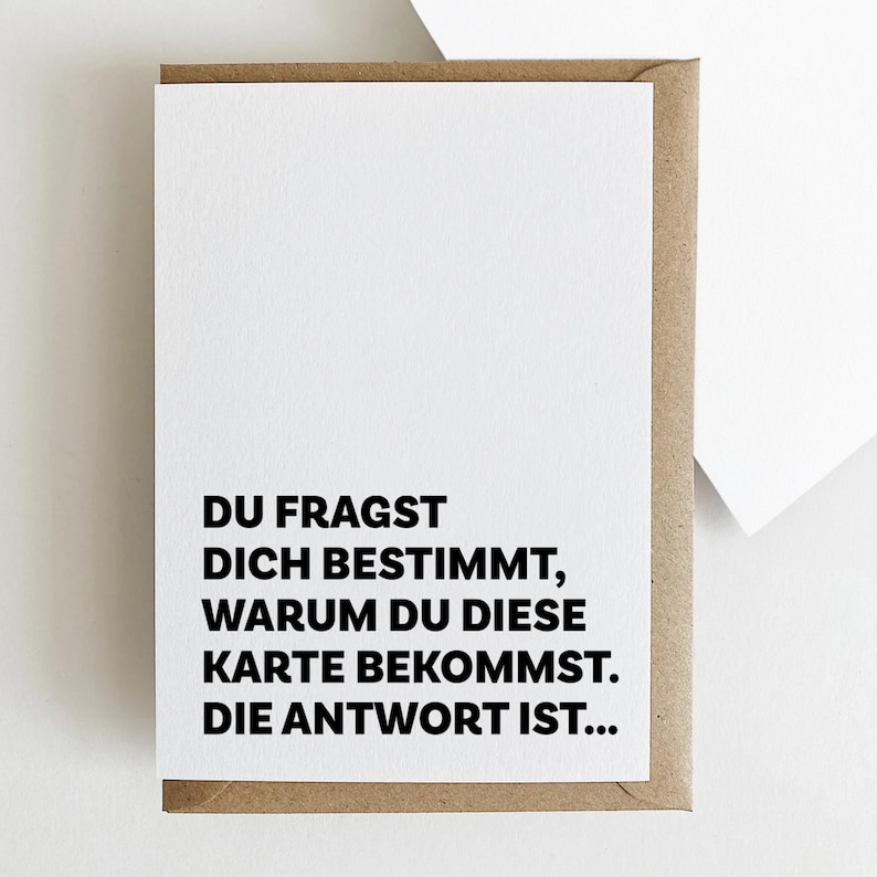 May include: A white card with black text that reads "DU FRAGST DICH BESTIMMT, WARUM DU DIESE KARTE BEKOMMST. DIE ANTWORT IST..."