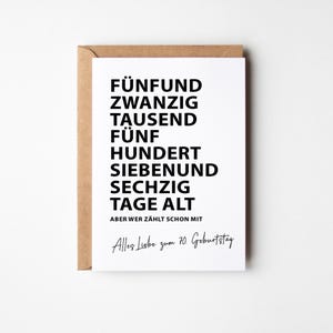 K&ouml;nnte beinhalten: Eine wei&szlig;e Gru&szlig;karte mit schwarzem Text, pr&auml;sentiert in einem braunen Umschlag. Der Text der Karte lautet "F&Uuml;NFUND ZWANZIG TAUSEND F&Uuml;NF HUNDERT SIEBENUND SECHZIG TAGE ALT" und "Alles Liebe zum 70. Geburtstag."
