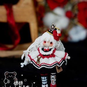 May include: A handmade doll with white hair, red eyes, and a black and white outfit. The doll has a small crown and a red bow. The doll's legs are patterned with diamonds and flowers. The background includes a wooden horse and red roses.