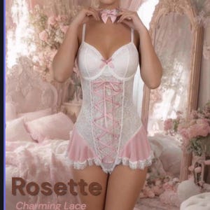 May include: A white lace bodysuit featuring a pink ribbon lace-up front, a pink ruffled hem, and a matching pink ribbon choker. The garment includes text that reads Rosette Charming Lace Pink Ruffle. The design has thin straps and a sweetheart neckline.