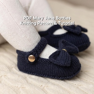 May include: A pair of dark navy blue knitted Mary Jane booties featuring a decorative bow on the front and a gold-colored button on the strap. The text PDF Mary Jane Botties Knitting Pattern & Tutorial is visible above the footwear.