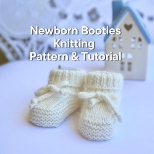 May include: A pair of white knitted baby booties with a bow on each. The booties are on a white surface. Newborn Booties Knitting Pattern & Tutorial.