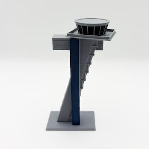 Op de afbeelding: Een 3D-geprint architectuurmodel in grijstinten en marineblauw. Het model heeft een gelaagde structuur met een cilindrisch element aan de bovenkant. Het ontwerp omvat een reeks trappen en een rechthoekige basis.
