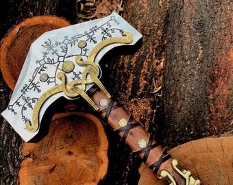 May include: A silver axe with a wooden handle wrapped in brown leather. The axe head is decorated with intricate patterns and has a gold-colored metal trim. The handle has a gold-colored metal pommel with a dragon design.