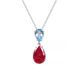 May include: A silver necklace featuring two pear-shaped gemstones. The top gemstone is light blue, and the bottom gemstone is a vibrant red. The necklace hangs from a delicate silver chain, creating an elegant and eye-catching design.